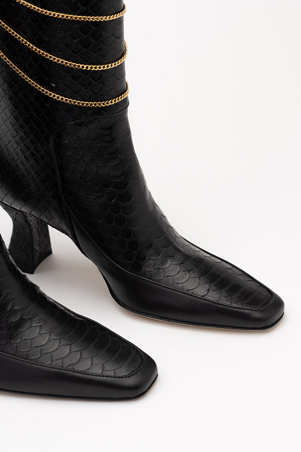 Focus on the sole of the calf high black boots Naomi Black Python Print Boot shot at an angle from the front on white background