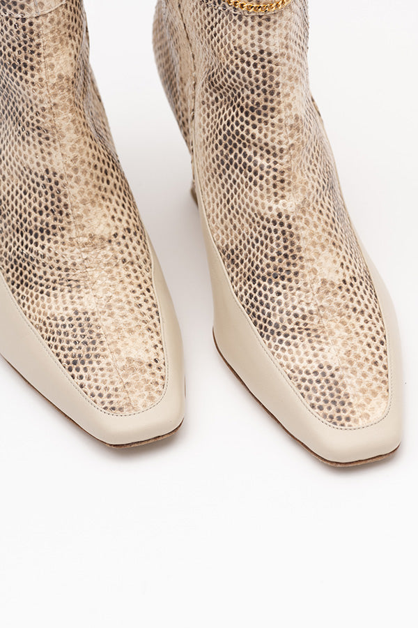Zoom-in from above at an angle on the sole of Naomi Python Print Ivory Boots on white background
